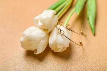 Tulips with golden bracelets on beige background, closeup