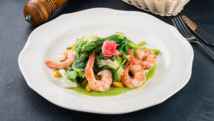 Lunch salad with shrimps, asparagus, lettuce and green sauce.