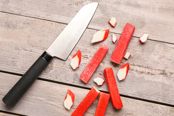 Tasty cut and whole crab sticks on light wooden background © Pixel-Shot