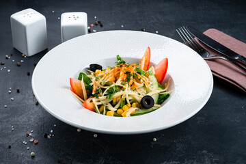 Salad of fresh cucumber, tomato, cheese, olives, corn and greens.