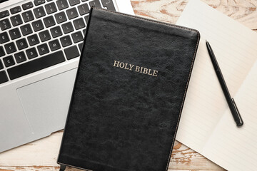 Holy Bible with notebook and laptop on white wooden background