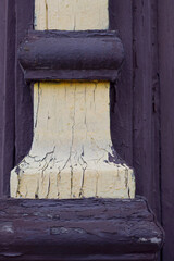 close up of an old architectural detail with painted wooden yellow and brown pillar