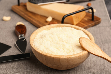 Bowl with tasty grated Parmesan cheese on table