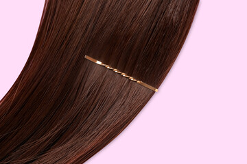 Brown hair with pin on lilac background, closeup
