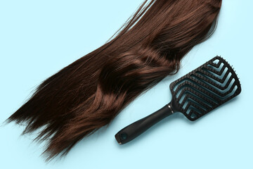 Wavy brown hair with brush on blue background