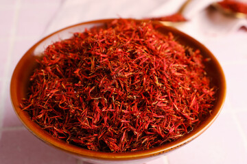 Fototapeta premium Bowl with pile of saffron on pink tile background