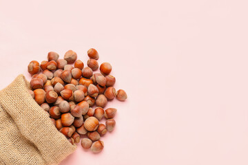 Sack bag with shelled hazelnuts on pink background