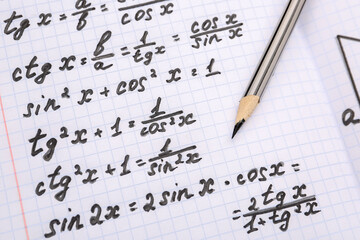 Copybook with maths formulas and pencil, closeup