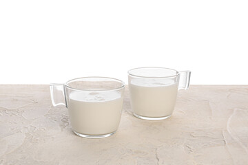 Cups of milk on table against white background