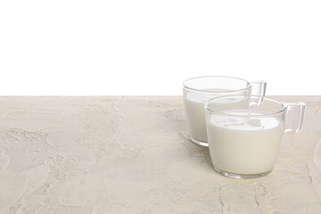 Cups of milk on table against white background