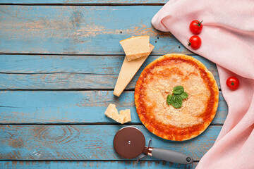 Tasty pizza with parmesan cheese, tomato, basil and cutter on blue wooden background