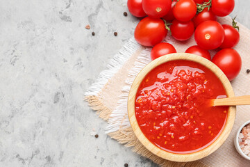 Bowl with tasty tomato sauce and fresh vegetables on grunge background