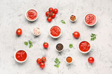 Bowls with tasty tomato sauce and ingredients on grunge background