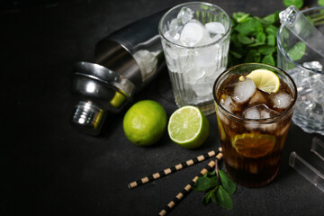 Glass of cold Cuba Libre cocktail on dark background