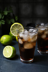 Glass of cold Cuba Libre cocktail on dark background