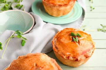 Tasty meat pot pies on green wooden background, closeup
