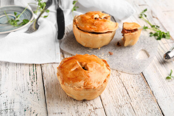 Tasty meat pot pies on light wooden background