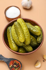 Bowl of tasty canned cucumbers with ingredients on beige background