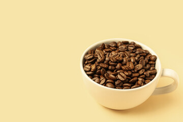 Cup with aromatic coffee beans on pale yellow background