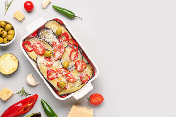 Baking dish with tasty Eggplant Parmesan and ingredients on light background
