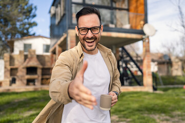 Happy Homeowner Man with Cup of Tea Stand in Front of Modern House