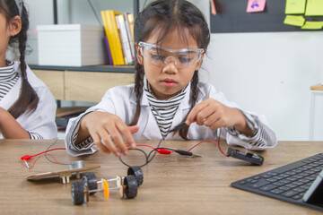 School student making robotic cars. Girl at robotics school makes robot managed from the constructor, child learns robot constructing.