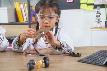 School student making robotic cars. Girl at robotics school makes robot managed from the constructor, child learns robot constructing.
