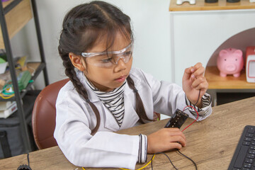School student making robotic cars. Girl at robotics school makes robot managed from the constructor, child learns robot constructing.