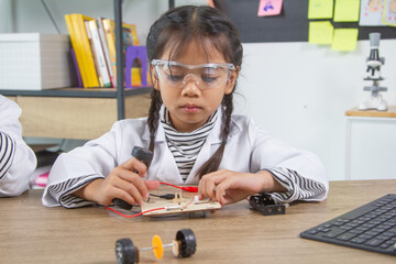School student making robotic cars. Girl at robotics school makes robot managed from the constructor, child learns robot constructing.