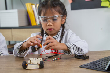 School student making robotic cars. Girl at robotics school makes robot managed from the constructor, child learns robot constructing.