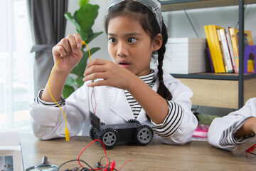 School student making robotic cars. Girl at robotics school makes robot managed from the constructor, child learns robot constructing.