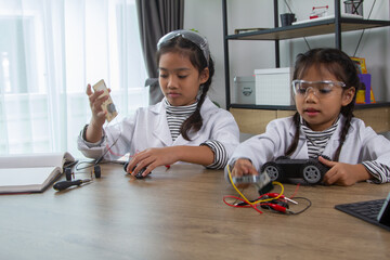 School student making robotic cars. Girl at robotics school makes robot managed from the constructor, child learns robot constructing.