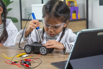 School student making robotic cars. Girl at robotics school makes robot managed from the constructor, child learns robot constructing.