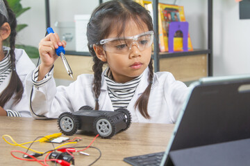 School student making robotic cars. Girl at robotics school makes robot managed from the constructor, child learns robot constructing.