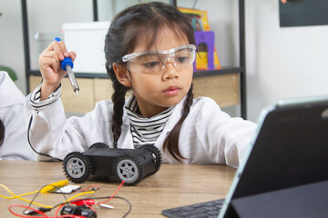 School student making robotic cars. Girl at robotics school makes robot managed from the constructor, child learns robot constructing.