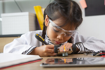 School student making robotic cars. Girl at robotics school makes robot managed from the constructor, child learns robot constructing.