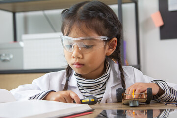 School student making robotic cars. Girl at robotics school makes robot managed from the constructor, child learns robot constructing.