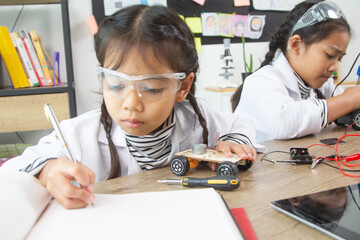 School student making robotic cars. Girl at robotics school makes robot managed from the constructor, child learns robot constructing.