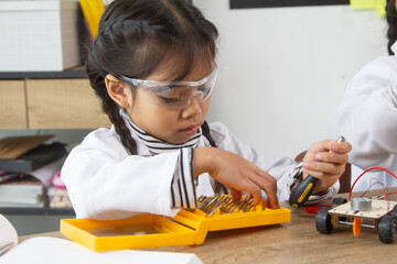 School student making robotic cars. Girl at robotics school makes robot managed from the constructor, child learns robot constructing.