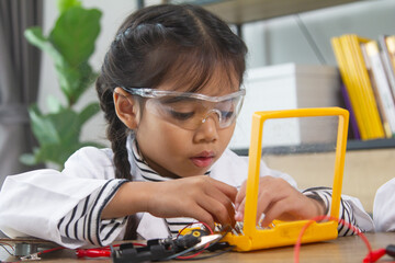School student making robotic cars. Girl at robotics school makes robot managed from the constructor, child learns robot constructing.