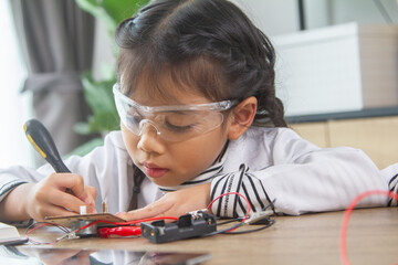 School student making robotic cars. Girl at robotics school makes robot managed from the constructor, child learns robot constructing.