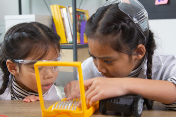 School student making robotic cars. Girl at robotics school makes robot managed from the constructor, child learns robot constructing.