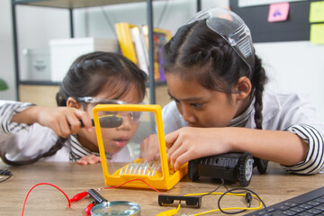 School student making robotic cars. Girl at robotics school makes robot managed from the constructor, child learns robot constructing.