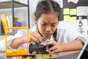 School student making robotic cars. Girl at robotics school makes robot managed from the constructor, child learns robot constructing.
