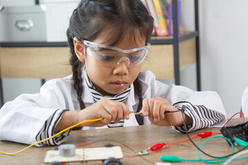 School student making robotic cars. Girl at robotics school makes robot managed from the constructor, child learns robot constructing.