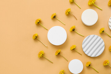 Decorative podiums with dandelion flowers on beige background
