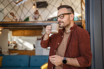 Happy 40-Year-Old caucasian Man Enjoying Tea or coffee on Balcony