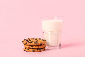 Glass of milk and cookies on pink background