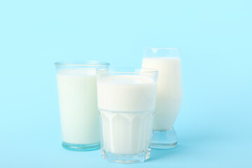 Glasses of milk on light blue background