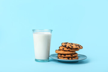 Glass of milk and cookies on light blue background